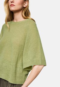 Light green knit sweater with short sleeves, relaxed fit, ribbed hem, and smooth texture. Accentuates shoulders with soft draping.