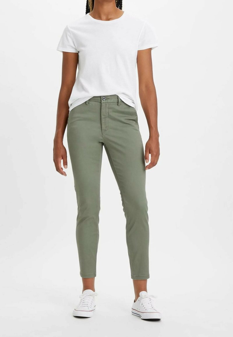 Olivgröna, tapered jeans i bomull med femfickorsdesign och knappstängning. Kombineras med en enkel vit T-shirt och sneakers.