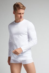 Witte katoenen shirt met lange mouwen en een ronde hals, gecombineerd met witte boxershorts. De stof lijkt glad en aansluitend op het lichaam.