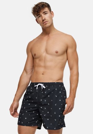 Black swim shorts featuring white anchor and letter patterns, elastic waistband with drawstring, and short-cut design.
