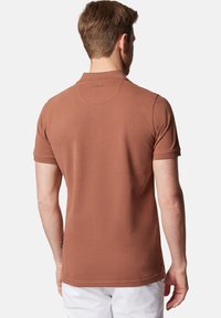 Brązowa koszulka polo z krótkim rękawem, z klasycznym kołnierzykiem, wykonana z gładkiego materiału, z subtelnym logo marki na dolnej części karku.