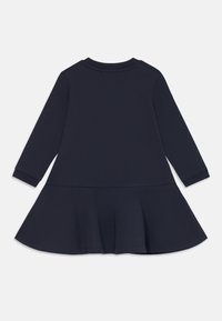 Marineblauwe jurk met lange mouwen en een uitlopende rok, van achteren weergegeven op een witte achtergrond.
