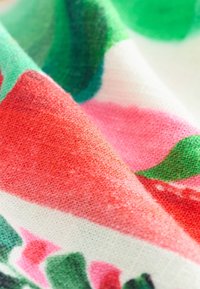 Bomullstyg med tät struktur och djärva röda, rosa och gröna abstrakta mönster som skapar en livfull och färgstark design.