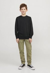 Felpa nera, pantaloni cargo verdi con tasche laterali e scarpe da ginnastica nere. Vestibilità casual, maniche lunghe e scollatura rotonda.