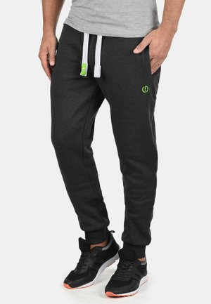 Dark gray jogger pants with white drawstrings, elastic cuffs, and side pockets. Features a small green logo on the left leg.