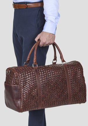 Brown woven leather duffel bag with sturdy brown handles, featuring a smooth leather accent and a zippered top closure.