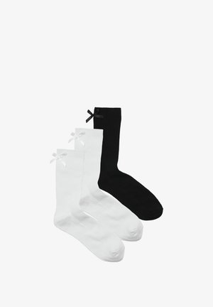 To sæt af bomuldsstrømper: et hvidt med en hvid sløjfe, et sort med en sort sløjfe. Begge har ribbet tekstur og standard crew-længde design.