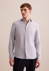 Camicia a maniche lunghe grigia chiara in tessuto testurizzato, con una chiusura a bottoni e colletto classico. Vestibilità sartoriale.