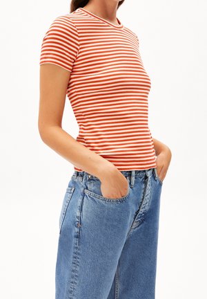 Czerwono-biała pasiasta koszulka z krótkim rękawem i okrągłym dekoltem, zestawiona z jasnoniebieskimi, wysokim stanem jeansami.