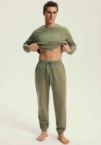 Green cotton loungewear set featuring a long-sleeve shirt with "CHOOSE YOUR PATH" print and matching drawstring pants; relaxed fit.