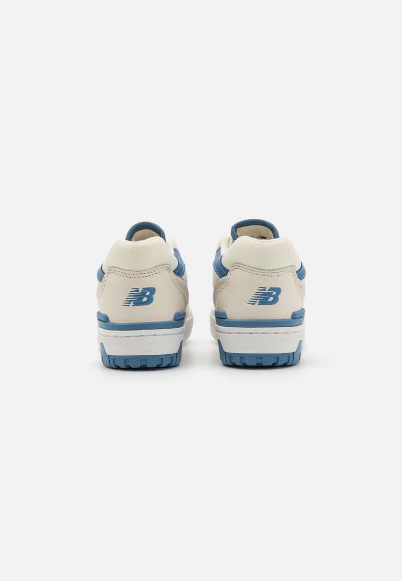 Scarpe da ginnastica con tomaia in pelle crema e dettagli blu, tallone imbottito e suola in gomma texturizzata. Logo del marchio sul tallone.