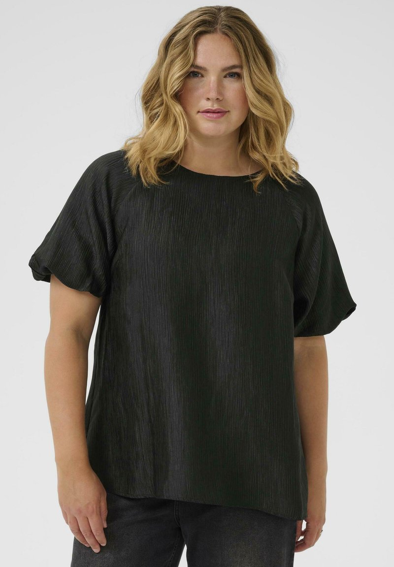 Schwarze Bluse mit strukturiertem, plissiertem Design. Verfügt über einen runden Ausschnitt und kurze Puffärmel. Kombiniert mit dunklen, eng anliegenden Jeans.