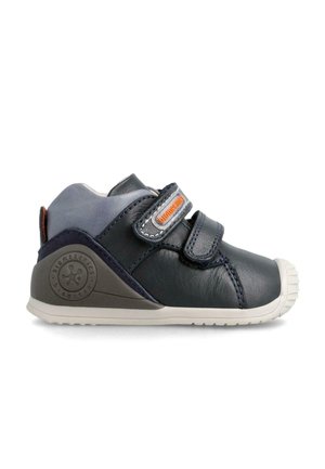 Zapatilla: zapatilla de cuero azul marino con correas de velcro, acentos grises, suela de goma texturizada, punta redondeada y detalle del logo en el lateral.