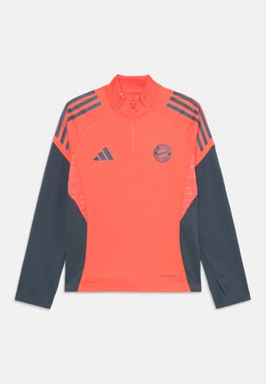 Jaco de FC Bayern Munich, com design de meia-zíper, corpo em coral vibrante, mangas em azul-marinho e painéis laterais em malha com detalhes do logotipo.