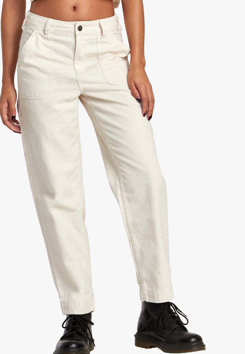 Witte, rechtlopende katoen broek met een hoge taille, voorzien van zijzakken en een knoopsluiting. Gecombineerd met stevige zwarte laarzen.