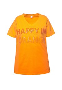 T-shirt orange à col en V avec des manches courtes, arborant l'inscription "HEUREUX EN ORANGE" en lettres à sequins sur la poitrine. Matière en coton doux.