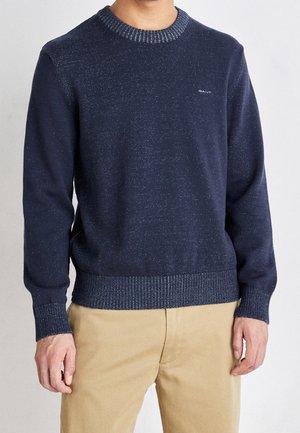 Marineblauer Pullover mit strukturiertem Finish, geripptem Halsausschnitt und Bündchen sowie subtilen helleren Sprenkeln. Verfügt über ein Logo auf der Brust und eine klassische Silhouette.