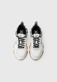 Pair of white and beige sneakers with black laces and logo text, viewed from above on a plain white background.