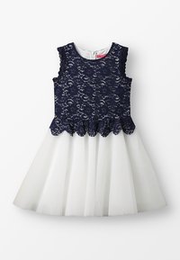 Šaty s námořnickým krajkovým korzetem a květinovými vzory, s vroubkovaným lemem a bílou tylovou sukní. Kulatý výstřih a zapínání na zip na zádech.