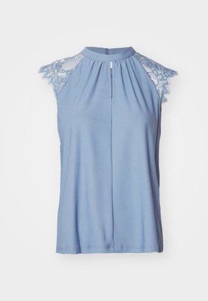 Lyseblå ermeløs topp med blonde cap-ermer, høy hals, frontfold og knappelukk bak. Myk, jevn stoff.
