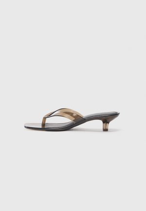 Transparent heeled flip-flop with a thin strap design, featuring a black footbed and light brown accents, offering a minimalist aesthetic.