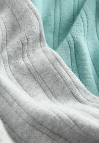 Szary i miętowozielony dzianinowy materiał o teksturowanej powierzchni, z pionowymi żebrowanymi wzorami oraz miękkimi, gładkimi powierzchniami.