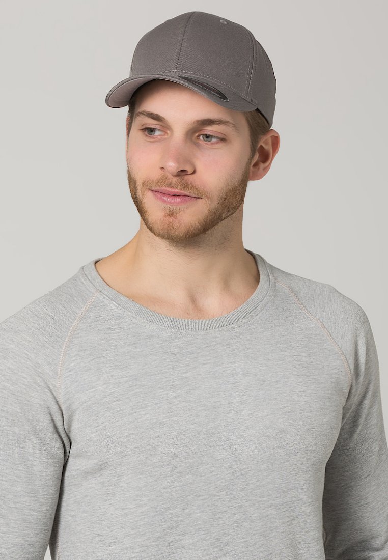 Cappellino da baseball grigio con visiera curva, realizzato in un tessuto morbido. Indossato con una felpa grigia chiara, caratterizzata da un collo rotondo e maniche raglan.