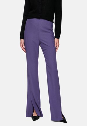 Purple, high-waisted trousers with a straight leg and slight side slits at the hem, paired with a black textured cardigan.