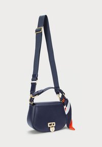 Navy leather crossbody bag with gold hardware, rounded shape, adjustable strap, and a patterned silk scarf attached.