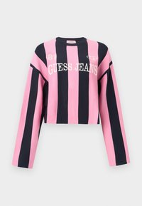 Κοντή ζακέτα με μακριά μανίκια, με εναλλασσόμενες κάθετες ροζ και ναυτικές ρίγες. Το κείμενο γράφει «GUESS JEANS» με άσπρα γράμματα. Μαλακό πλεκτό υλικό.