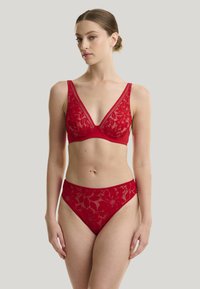Brassière en dentelle rouge et culottes taille haute assorties. Motif floral, bords festonnés et texture douce. Design en V avec bretelles larges.
