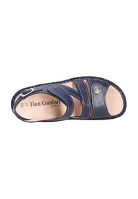 Marineblauwe lederen sandaal met brede banden, verstelbare gespsluiting en een getextureerde binnenzool. Bevat een ronde embleem en contrasterende stiksels.