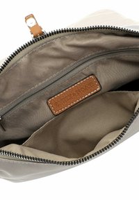 Una borsa in tessuto beige con una cerniera scura, dotata di un'etichetta in pelle marrone cucita all'interno con la scritta "EMILY & NOAH" in rilievo. Interno foderato.