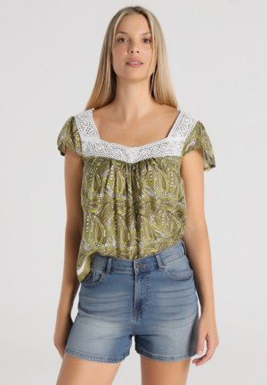 Blusa verde con estampado de cachemira y adornos de encaje blanco en el escote, de mangas cortas, combinada con pantalones cortos de mezclilla.