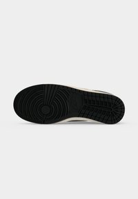 Μαύρη λαστιχένια σόλα ενός sneaker Nike με κυκλικά και πλέγμα μοτίβα πέλματος και το λογότυπο της Nike στο κέντρο.