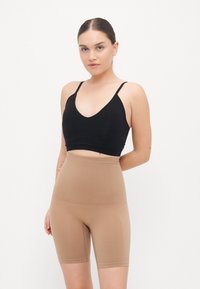 Top corto nero con spalline sottili abbinato a pantaloncini da ciclismo a vita alta, senza cuciture, di colore marrone chiaro, texture liscia, design minimalista.