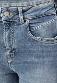 Light blue denim jeans featuring a sturdy waistband, metal button closure, and front pockets with visible stitching and faded texture.
