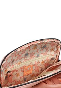 Bolso de color rosa con un exterior acolchado. En el interior presenta un patrón floral, un pequeño bolsillo con cremallera y una etiqueta de marca naranja.