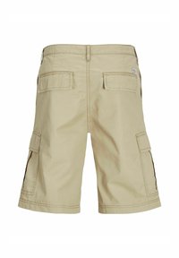 Short cargo beige avec poches à rabat à l'arrière et sur les côtés, coutures visibles et petite étiquette en tissu sur la poche arrière droite.