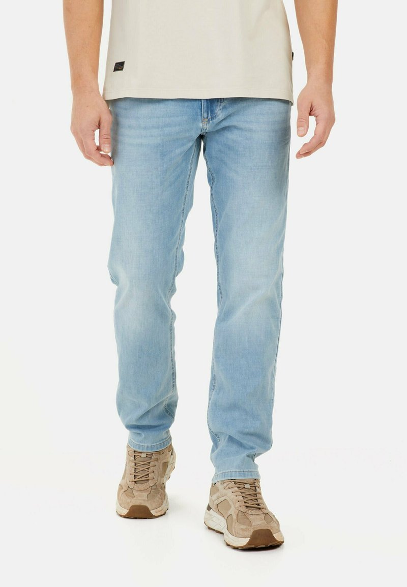 Jasnoniebieskie dżinsy o prostym kroju, z subtelnym efektem przytartego materiału. Połączone z beżowymi sneakersami.