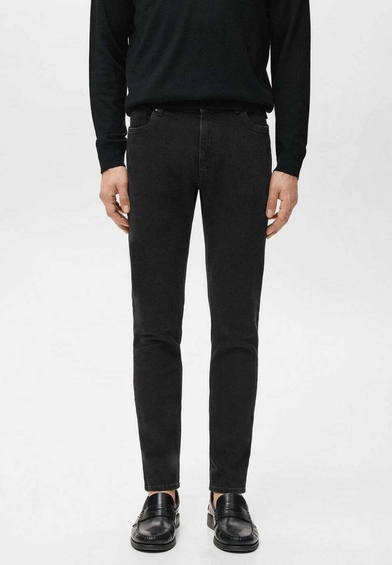 Jeans ajustados negros con una textura suave, con una pretina estándar y detalles sutiles de costura, combinados con mocasines negros.