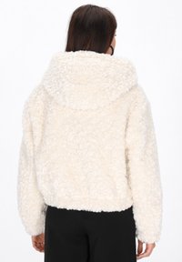 Crème-kleurige, pluffy fleecejas met een grote capuchon, verlaagde schouders en een cropped silhouet, voorzien van zachte, gestructureerde stof.