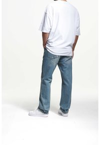 Valkoinen ylisuurikokoinen t-paita, siniset farkut ja valkoiset lenkkarit. Pehmeää puuvillakangasta, rento istuvuus, suorat lahkeet haalistuneilla yksityiskohdilla.