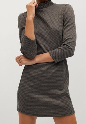 Robe à carreaux noir et blanc avec un col montant à volants, des manches trois-quarts et une silhouette ajustée. Texture de tissu lisse.