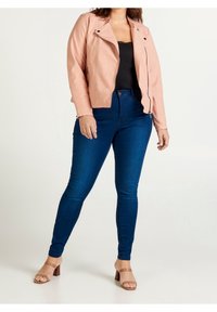 Różowa kurtka z ekologicznej skóry z zamkami błyskawicznymi, czarna bluzka z koronki oraz niebieskie obcisłe dżinsy. Całość uzupełniona brązowymi sandałami na szerokim obcasie.