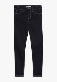 Jeans de mezclilla de color azul oscuro, con costuras blancas, un diseño clásico de cinco bolsillos y un cierre de botón en la cintura.