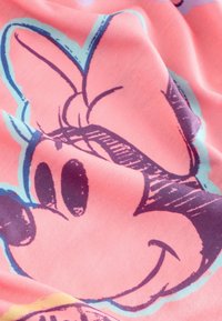 Tissu corail présentant le visage stylisé d'un personnage avec de grands yeux noirs et un sourire, entouré de contours bleu sarcelle et violet, avec une texture lisse.