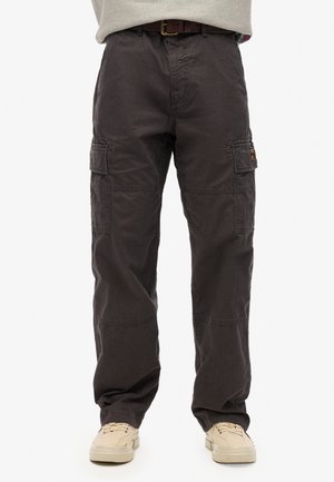 Dunkle Cargo-Hosen mit geradem Schnitt und seitlichen Klappentaschen, getragen mit beigen Sneakers und braunem Ledergürtel.