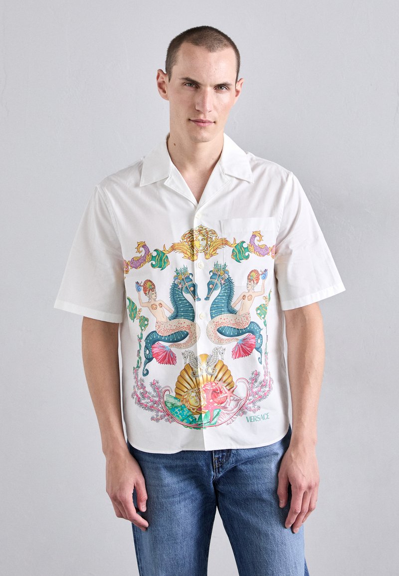 Short-sleeve white shirt featuring a colorful, intricate graphic design of mermaids, seahorses, and shells; lightweight fabric, relaxed fit.