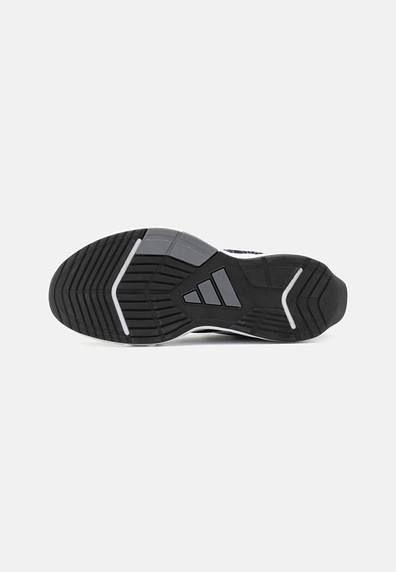Schwarze Sneaker-Außensohle mit einer strukturierten Gummioberfläche, die ein geometrisches Profilmuster und weiße Akzente aufweist, entworfen für Traktion und Langlebigkeit.